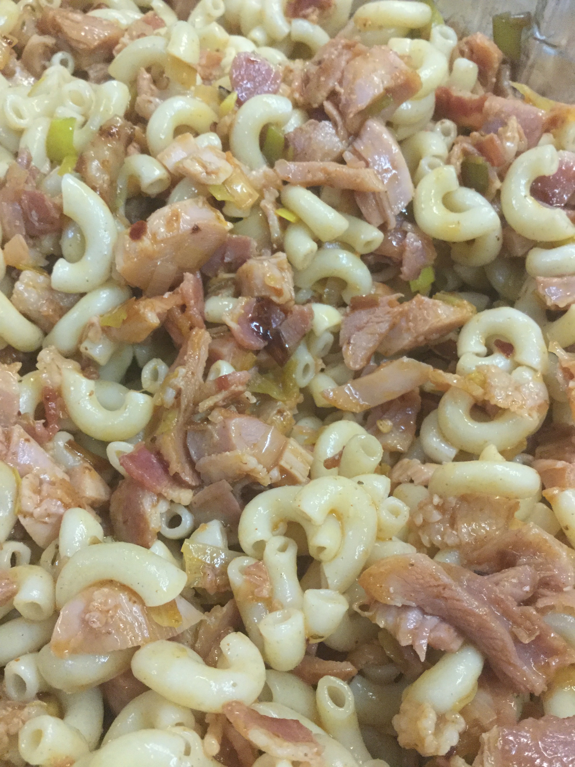 a mixture of cooked macaroni pasta tossed with cooked bacon, smoked chicken, and sautéed leeks